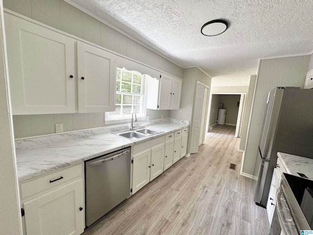 kitchen featuring stainless steel appliances, light hardwood / wood-style floors, white cabinetry, sink, and a textured ceiling