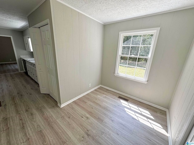 spare room with crown molding, a textured ceiling, hardwood / wood-style floors, and wooden walls