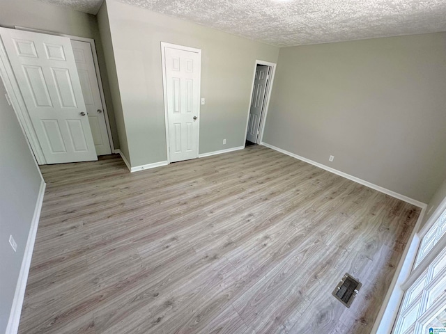 unfurnished bedroom featuring a textured ceiling and light hardwood / wood-style flooring