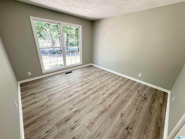 unfurnished room featuring a textured ceiling and hardwood / wood-style floors