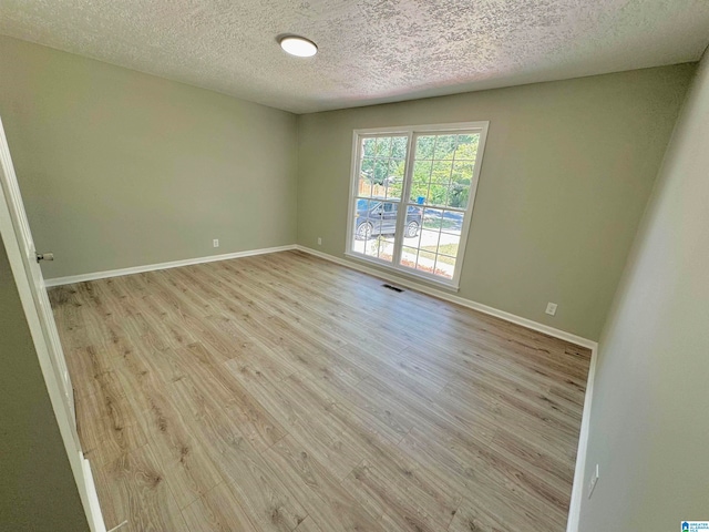 empty room with a textured ceiling and light hardwood / wood-style floors