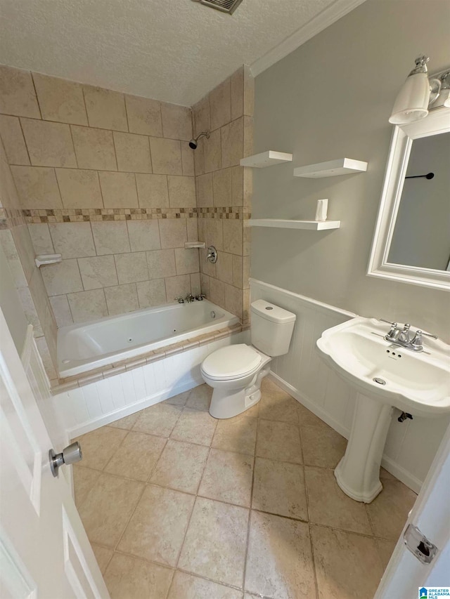 full bathroom featuring tiled shower / bath combo, toilet, tile patterned flooring, and a textured ceiling