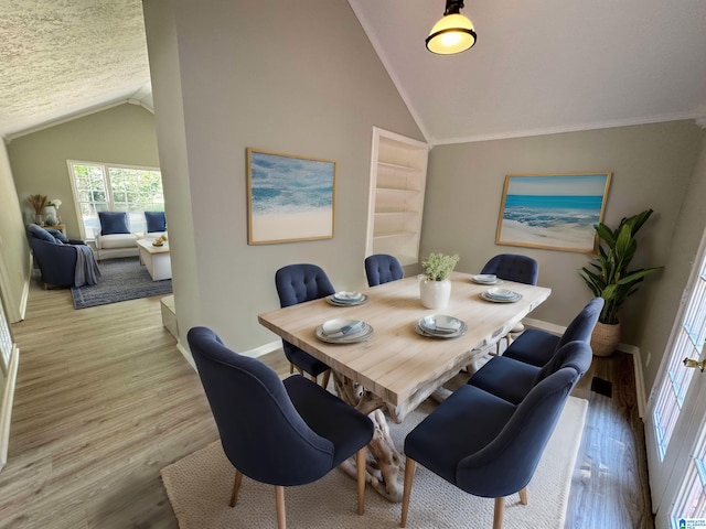 dining room featuring ornamental molding, a textured ceiling, lofted ceiling, and light hardwood / wood-style floors