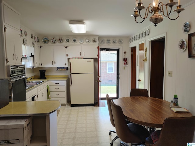 kitchen with ornamental molding, white cabinetry, a notable chandelier, and white fridge