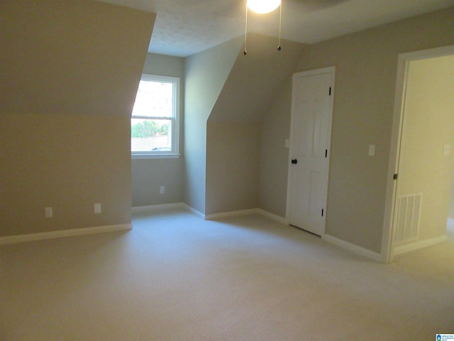 additional living space featuring vaulted ceiling, light colored carpet, ceiling fan, and a textured ceiling