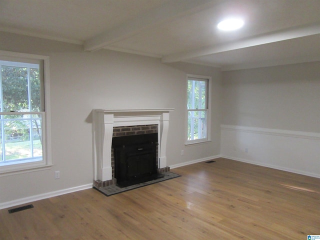 unfurnished living room with hardwood / wood-style floors, a wealth of natural light, and beam ceiling