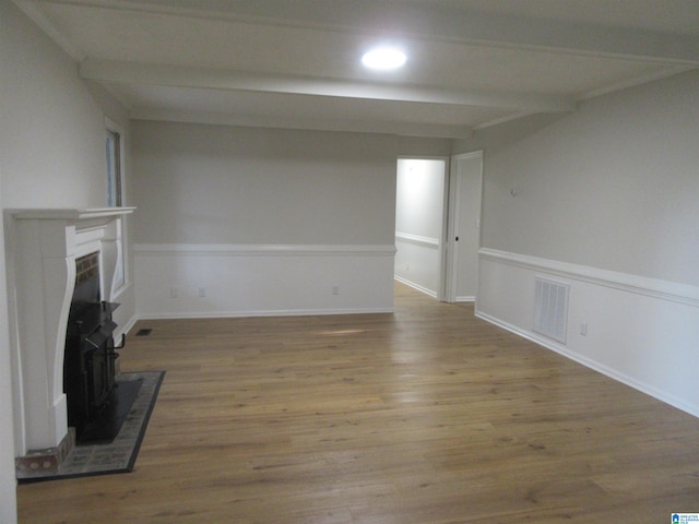 unfurnished living room featuring beamed ceiling and light hardwood / wood-style flooring