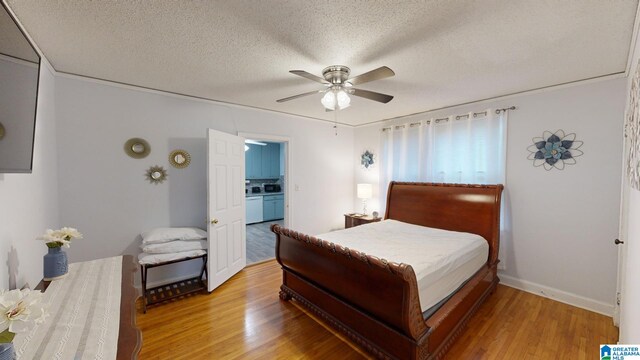 bedroom with light wood-type flooring, ceiling fan, ensuite bath, and a textured ceiling