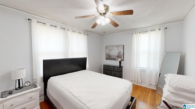 bedroom with light wood-type flooring, crown molding, a textured ceiling, and ceiling fan