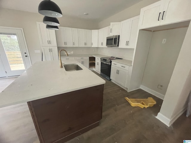 kitchen featuring decorative light fixtures, white cabinetry, appliances with stainless steel finishes, and a kitchen island with sink