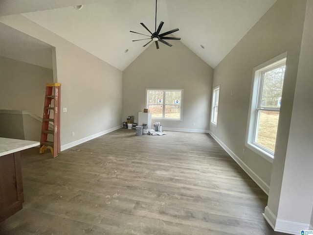 unfurnished living room with vaulted ceiling, ceiling fan, a wealth of natural light, and wood-type flooring