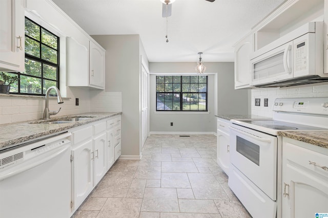 kitchen with white appliances, white cabinetry, sink, and a wealth of natural light