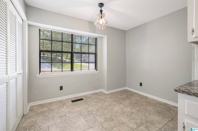 unfurnished dining area featuring a chandelier