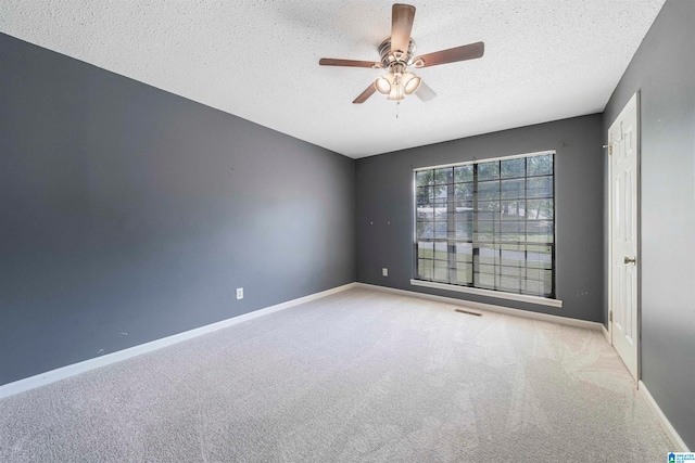 spare room featuring ceiling fan, a textured ceiling, and light colored carpet