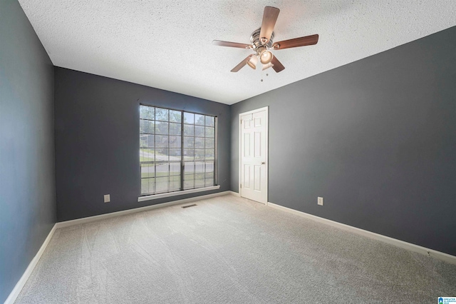 empty room with ceiling fan, a textured ceiling, and carpet flooring