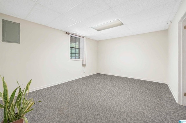 carpeted spare room with a paneled ceiling and electric panel