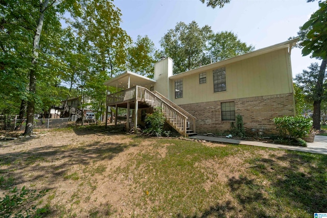 rear view of house featuring a wooden deck and a yard