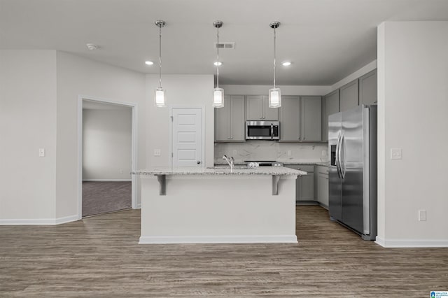 kitchen featuring gray cabinetry, stainless steel appliances, a breakfast bar area, and an island with sink