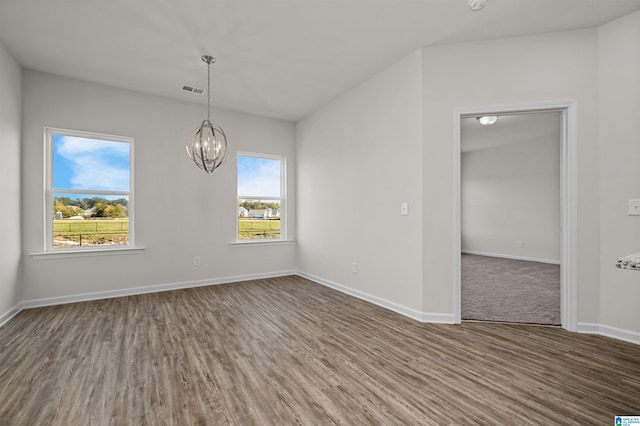 spare room with dark hardwood / wood-style flooring and an inviting chandelier