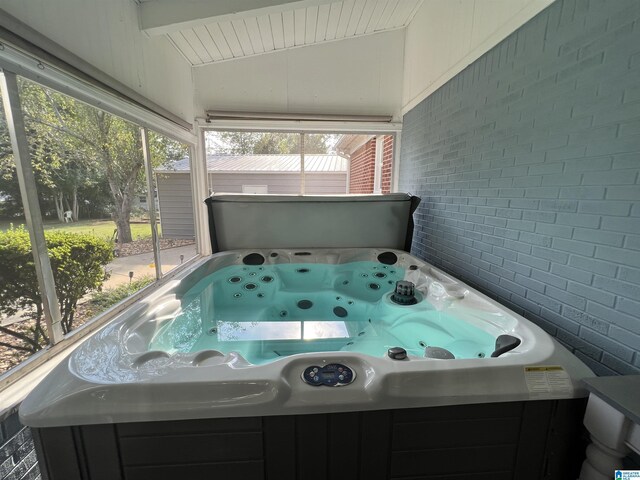 unfurnished sunroom with vaulted ceiling and a hot tub