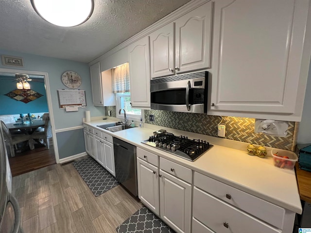 kitchen featuring light hardwood / wood-style flooring, appliances with stainless steel finishes, sink, white cabinetry, and ceiling fan