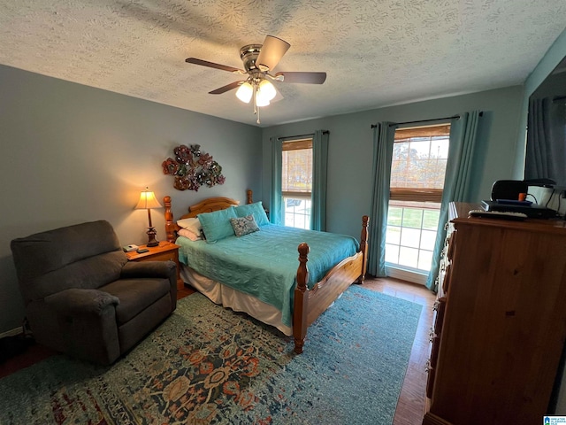 bedroom with a textured ceiling, ceiling fan, and hardwood / wood-style flooring