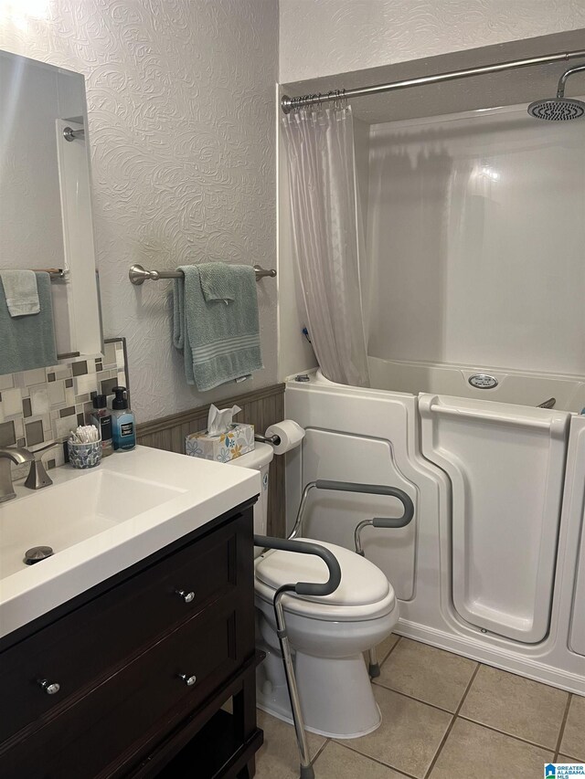 full bathroom with toilet, tile patterned floors, vanity, shower / bath combo with shower curtain, and decorative backsplash