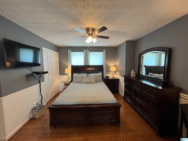 bedroom featuring a closet, ceiling fan, dark hardwood / wood-style floors, and a textured ceiling