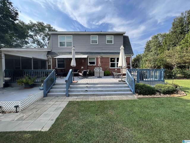 rear view of house featuring a yard, a sunroom, and a deck