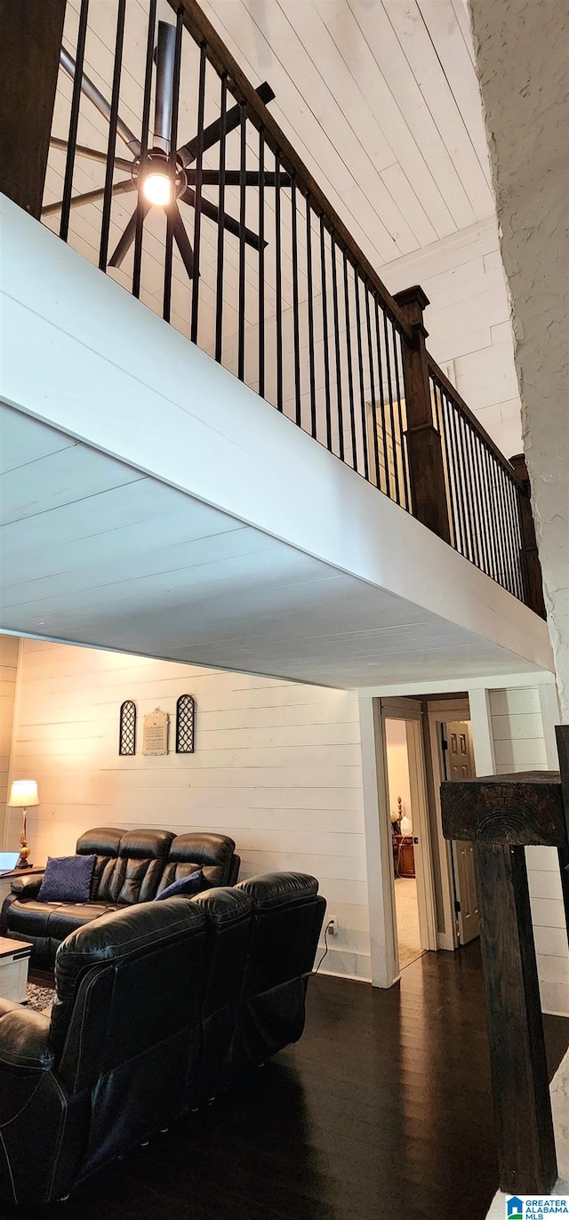 interior space featuring wood walls, ceiling fan, wood-type flooring, and a towering ceiling