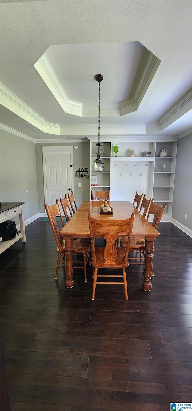 dining room with a tray ceiling, dark hardwood / wood-style flooring, a textured ceiling, and ornamental molding