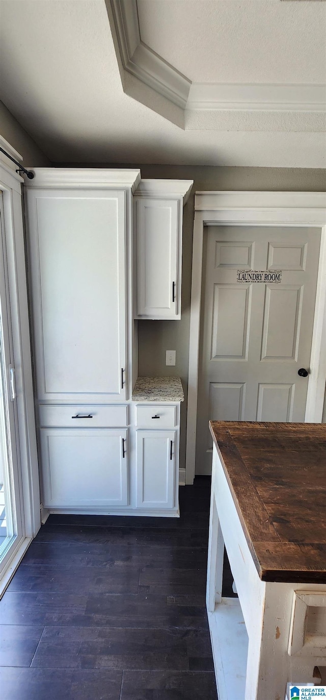 kitchen featuring dark wood finished floors, light stone countertops, white cabinetry, black appliances, and a sink
