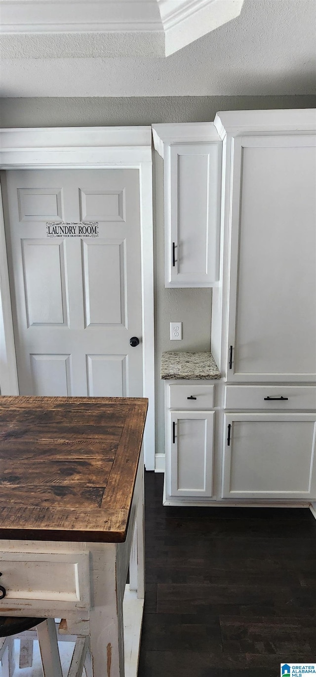 kitchen featuring butcher block counters, dark wood-style flooring, and white cabinets