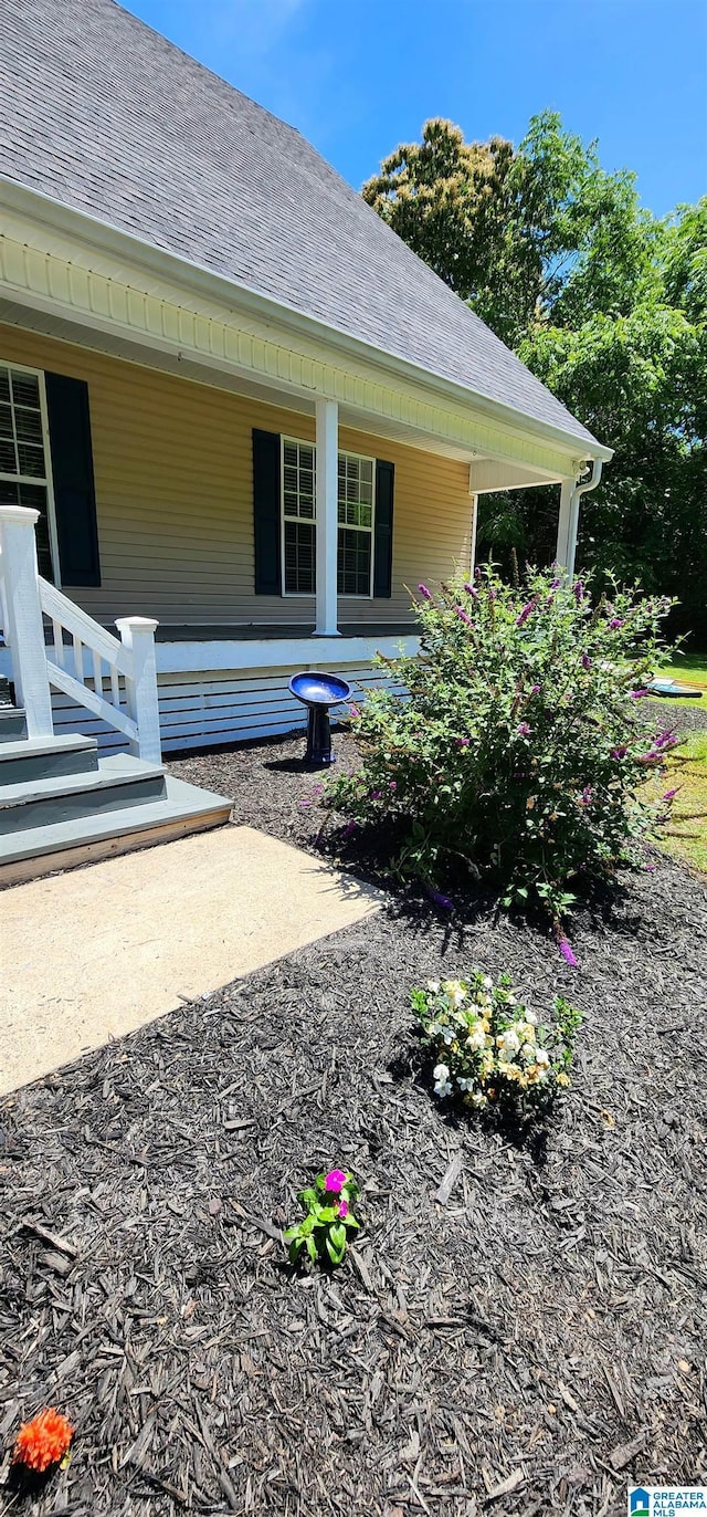 view of side of property with a porch and a shingled roof
