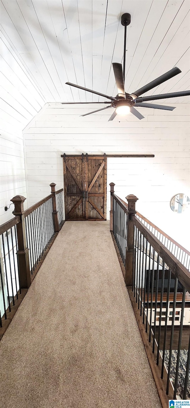 corridor with lofted ceiling, wood walls, and carpet flooring