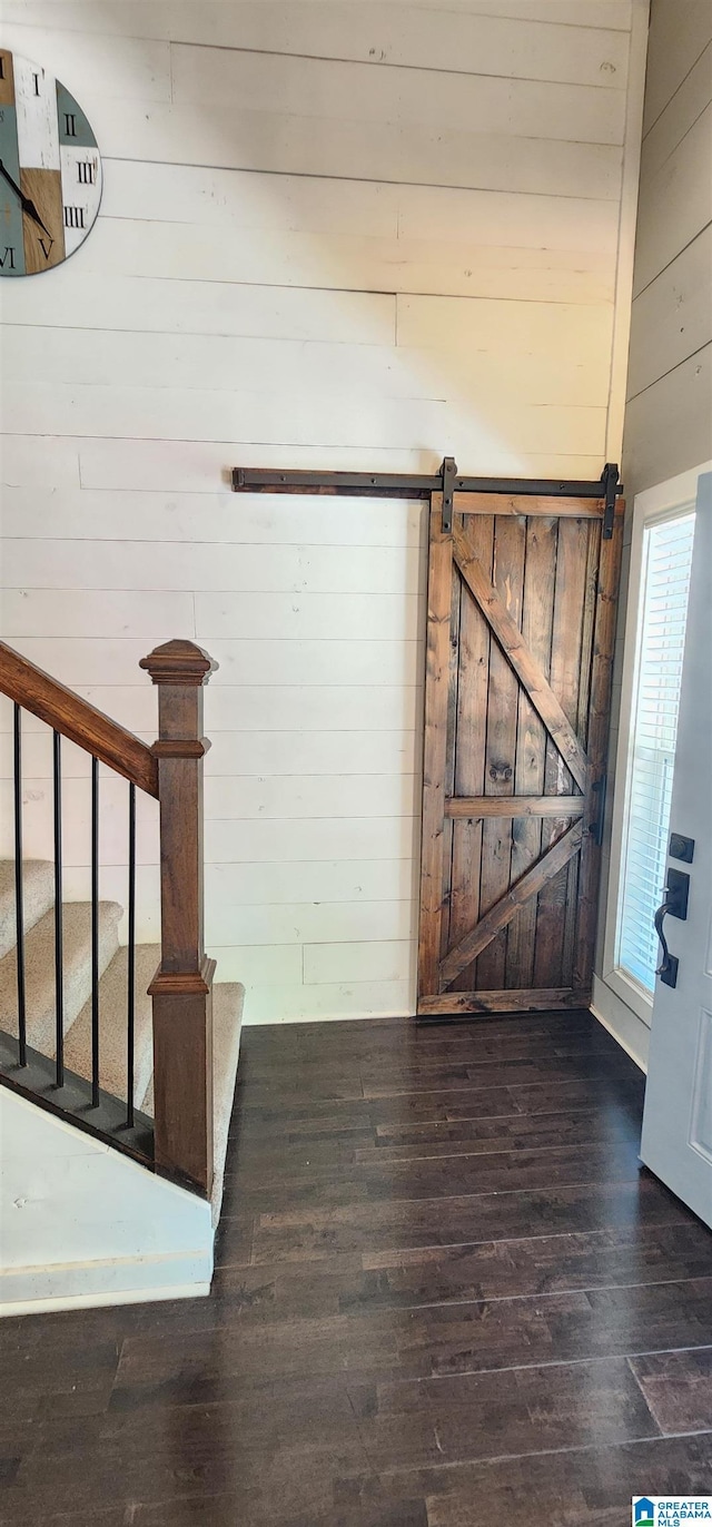 foyer featuring wood finished floors, wooden walls, and stairway