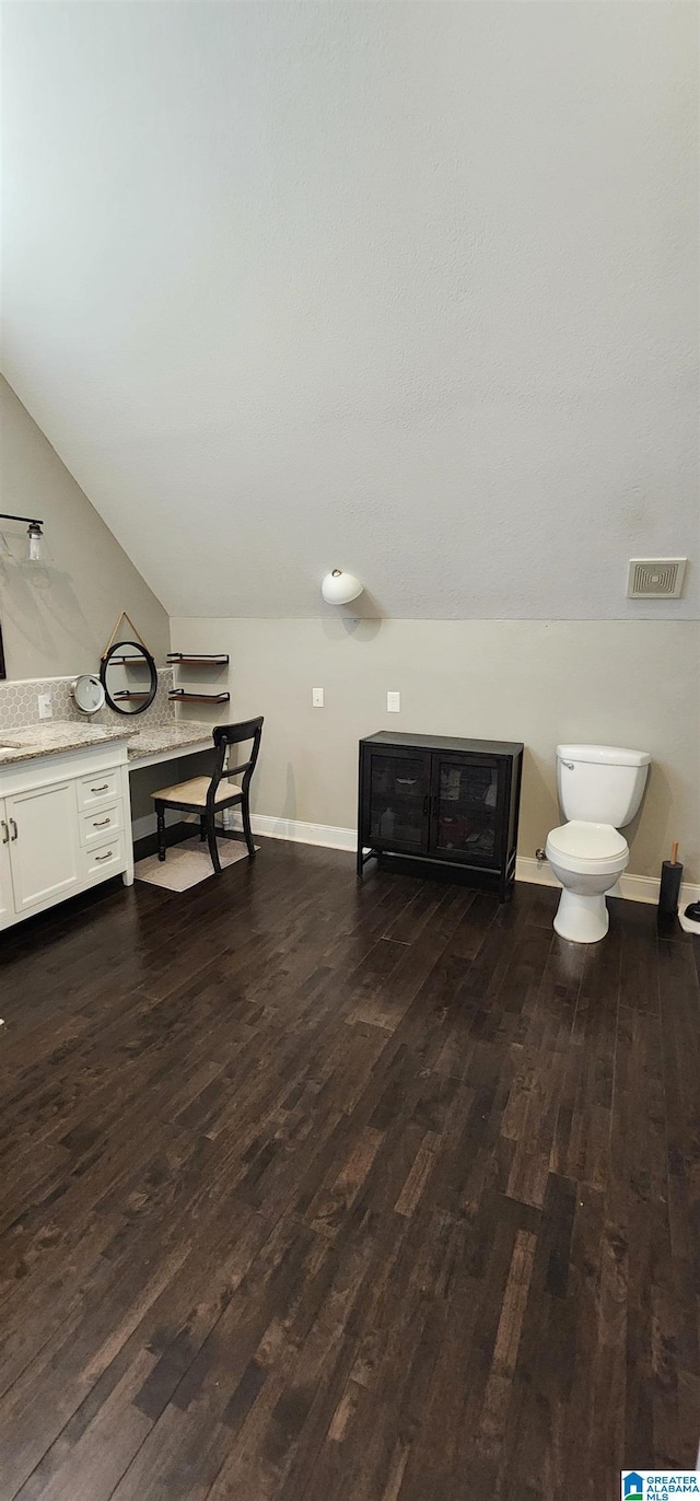 bathroom with visible vents, baseboards, toilet, vaulted ceiling, and wood-type flooring