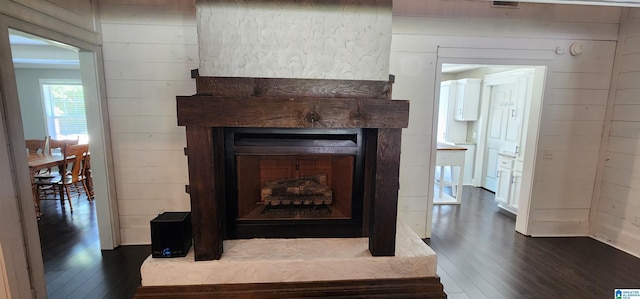 room details featuring wood finished floors, wooden walls, and a fireplace with raised hearth