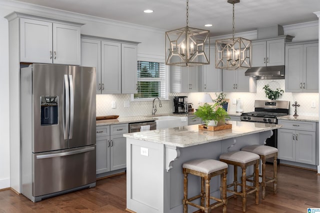 kitchen featuring a center island, appliances with stainless steel finishes, dark wood-type flooring, and a notable chandelier