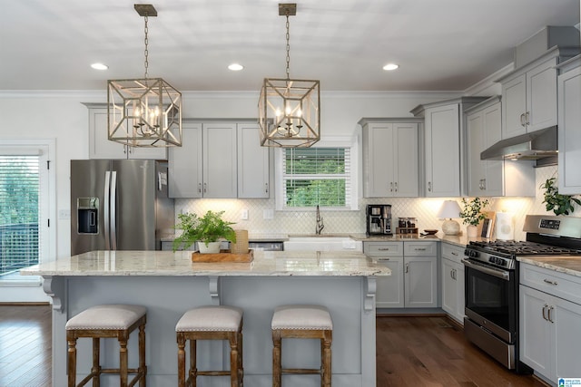 kitchen with pendant lighting, dark hardwood / wood-style flooring, a kitchen island, an inviting chandelier, and appliances with stainless steel finishes