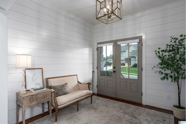 entryway featuring wood walls, hardwood / wood-style flooring, crown molding, and a notable chandelier