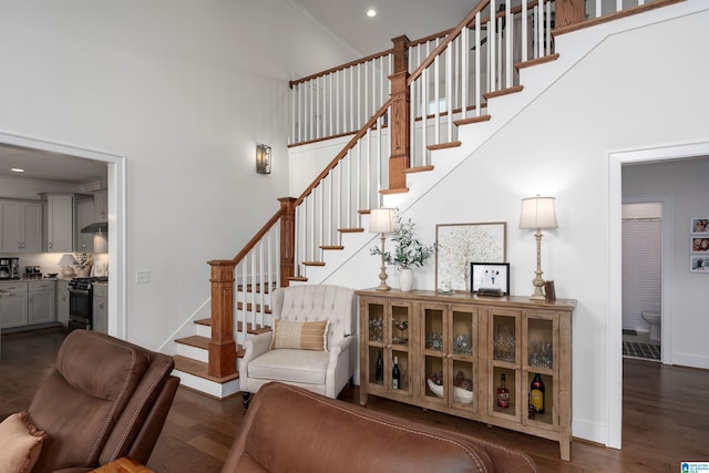 stairs with crown molding, a high ceiling, and hardwood / wood-style flooring