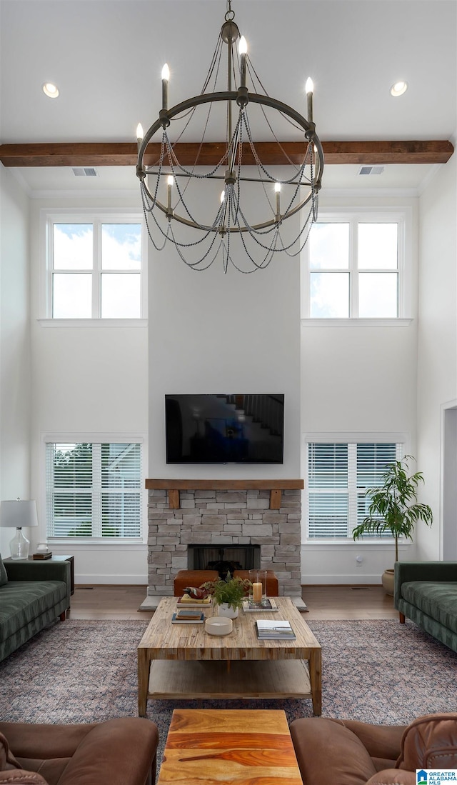 living room with a wealth of natural light, a fireplace, hardwood / wood-style flooring, and a notable chandelier