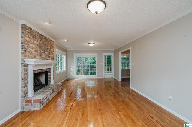 unfurnished living room with a textured ceiling, crown molding, light hardwood / wood-style floors, and a fireplace