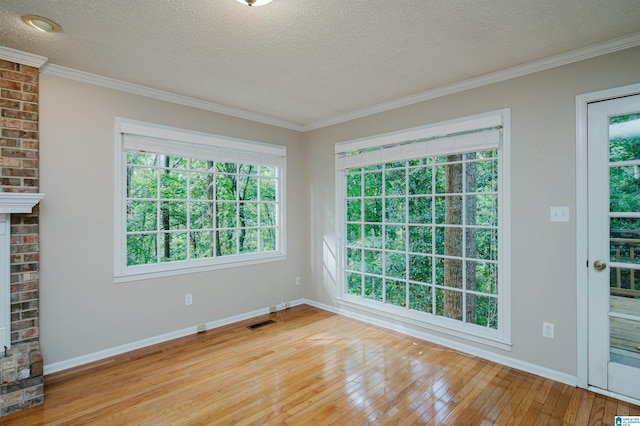 interior space featuring light hardwood / wood-style flooring, a fireplace, crown molding, and a textured ceiling