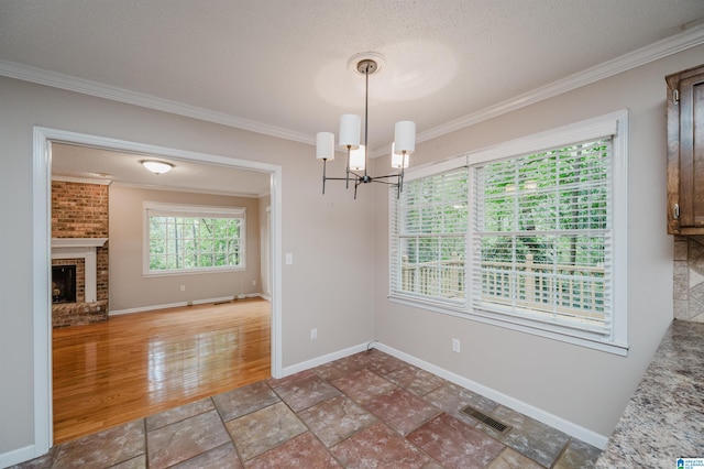 unfurnished dining area with a fireplace, crown molding, a textured ceiling, an inviting chandelier, and dark hardwood / wood-style floors