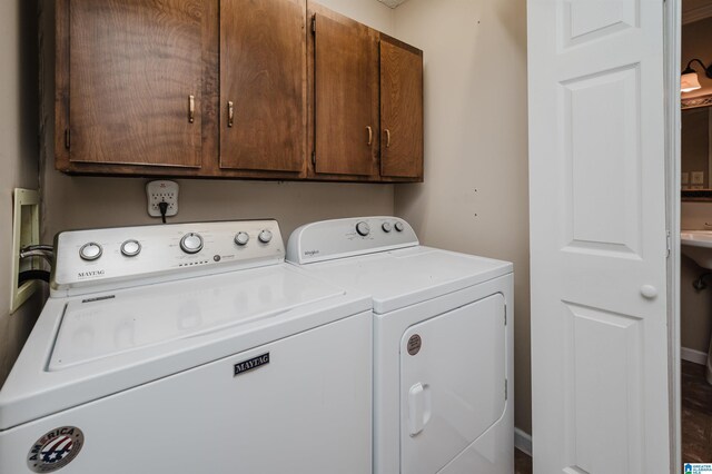 clothes washing area with washer and clothes dryer, hardwood / wood-style floors, and cabinets