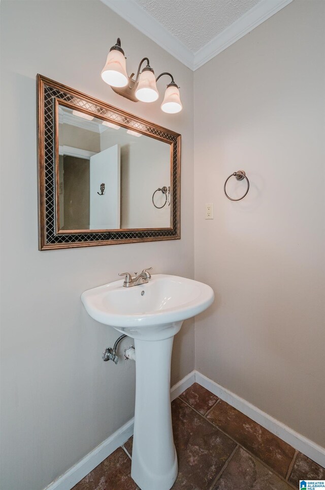 bathroom featuring a textured ceiling, ornamental molding, and sink