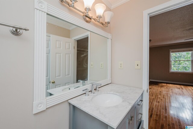 bathroom with hardwood / wood-style flooring, ornamental molding, a textured ceiling, and vanity