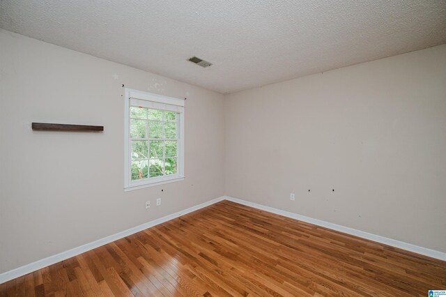 unfurnished room featuring a textured ceiling and hardwood / wood-style flooring